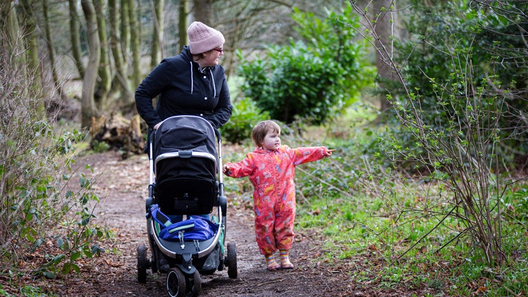 Woman pushing pram with your child at her side exploring the woodland at Moseley Old Hall, Staffordshire